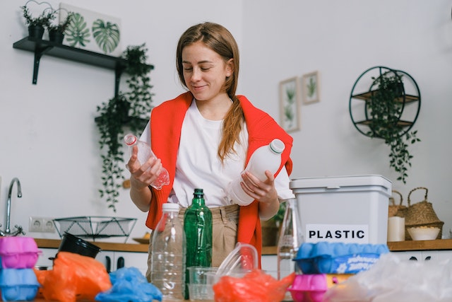 Smiling person holding two plastic bottles and sorting their recycling