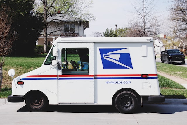 A USPS truck parked on the side of the road in a residential neighborhood